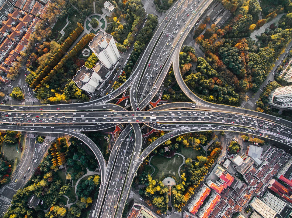 Foto aus der Luft eines rießigen, befahrenen Autobahnkreuz
   in Indonesien, umgeben von Häusern und Grünanlagen.