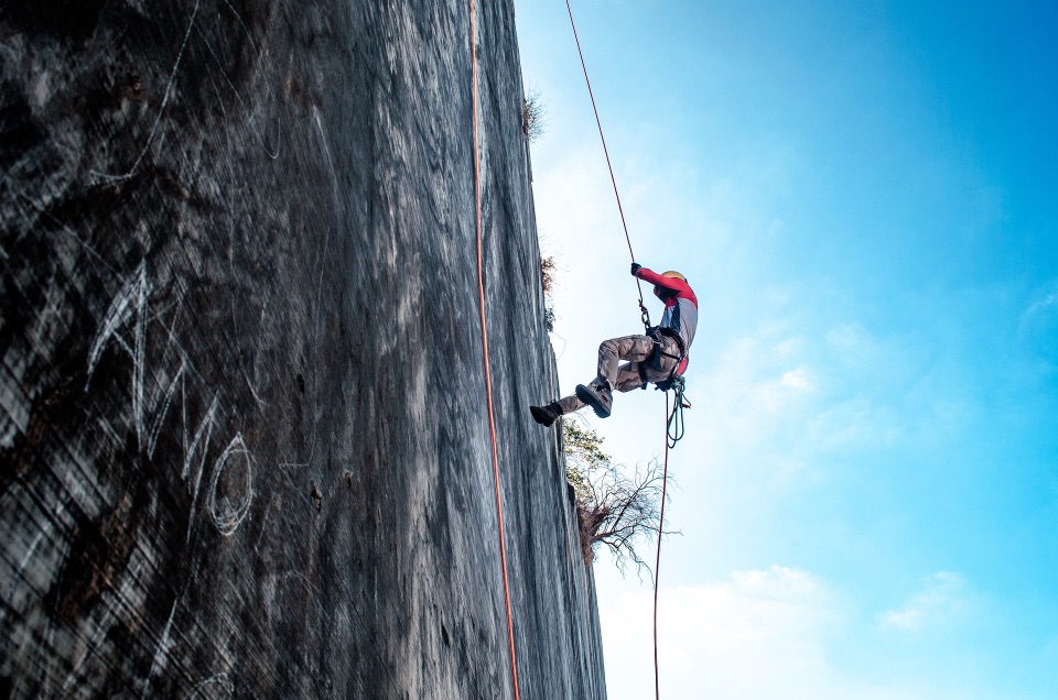 Ein Bergsteiger, der sich an einer Steinmauer abseilt